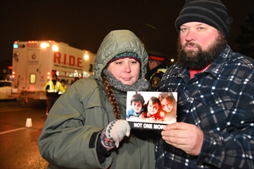 Jennifer Neville-Lake and her husband, Edward Lake, hold a photo of their three children in 2018.